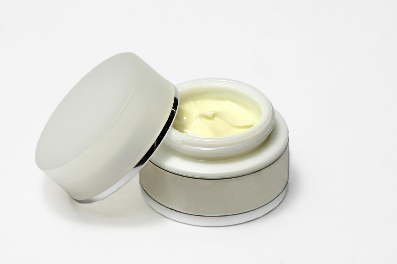 An open jar of face cream on a white surface