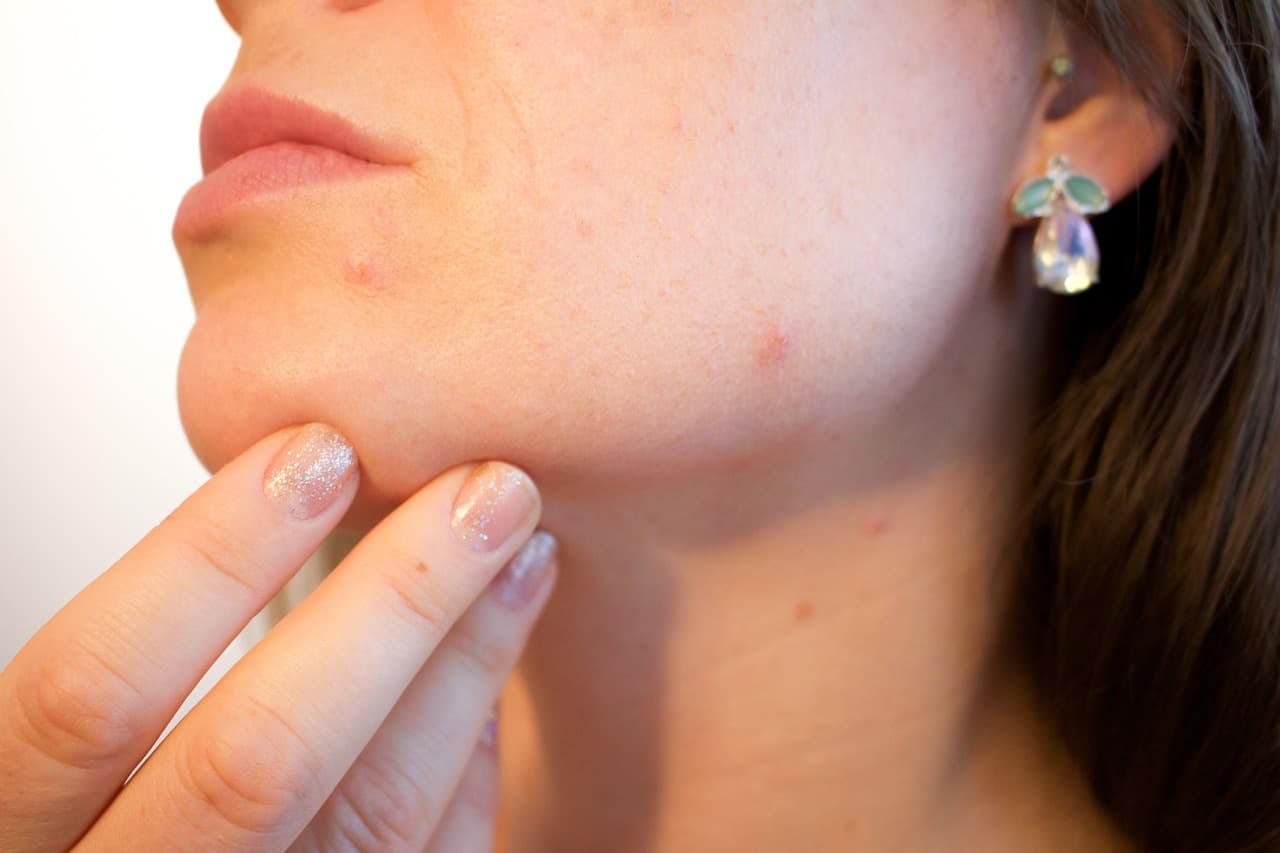 Fingertips resting along the jawline, natural skin in soft daylight